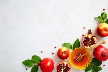 Rosh Hashanah Jewish New Year holiday concept. Flat lay composition with pomegranate, honey, apples, green leaves on stone background. Top view, copy space.