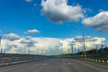 A long, empty highway with a blue sky and clouds