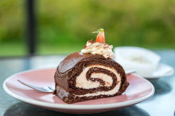 A slice of chocolate cake with whipped cream on top sits on a pink plate