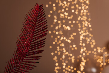A red glittery fern leaf against a backdrop of twinkling lights, ideal for festive decor or...