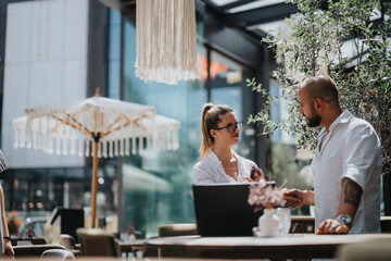 Two business professionals having a conversation at an outdoor cafe in a modern urban city. They are discussing work-related matters.