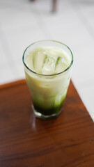a glass of fresh matcha flavored ice served on a table in a cafe