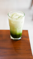 a glass of fresh matcha flavored ice served on a table in a cafe