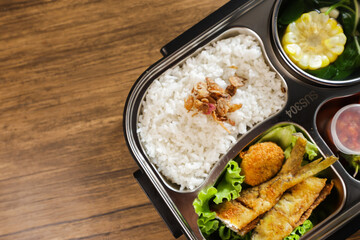 Lunch or bento is put in a lunch box. There are vegetables, side dishes, fruit and also rice.
