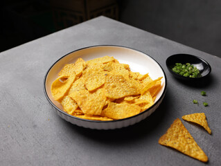 Savory salted corn chips on a plate with a plain background