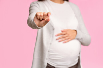 Unrecognizable Pregnant Girl Showing Medicine Pill To Camera Standing Over White Studio Background....