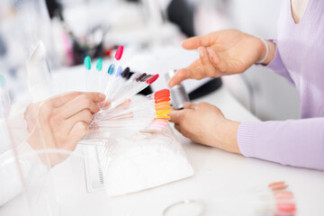 Palette with color schemes of lacquers in the hands of a female client. Close-up image