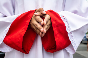 Detail of the hands of a Catholic priest during the procession of the Sacred Heart of Jesus in the...