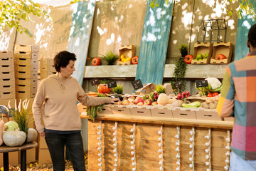 Multicultural consumers gather near the greenmarket booth to examine seasonal homegrown food...