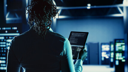 Knowledgeable woman running code on tablet, troubleshooting and upgrading high tech establishment...