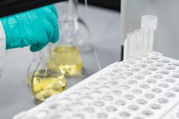 Woman hand takes tube from fraction collector connected to HPLC. 