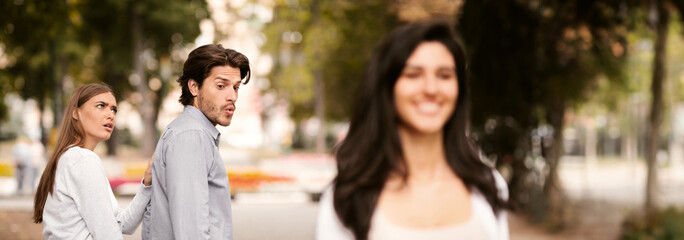 Jealousy. Jealous Girlfriend Calling Boyfriend Distracted By Other Attractive Woman Walking During Date In Park. Selective Focus