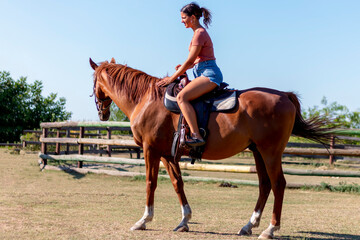 A beautiful girl riding her admirable big brown horse and training for the race on her ranch on the...