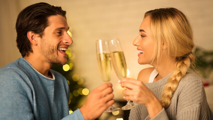 Happy spouses clinking champagne glasses, celebrating holidays together at home