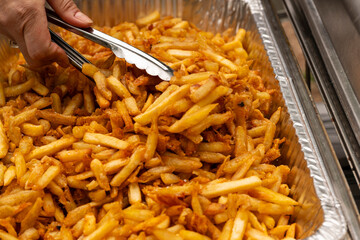 Party bowl with french fries. Tongs grabbing french fries.