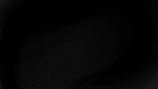 Black grainy background with faint white dots and a slight curve. Abstract background suitable for design projects, presentations, and digital art.