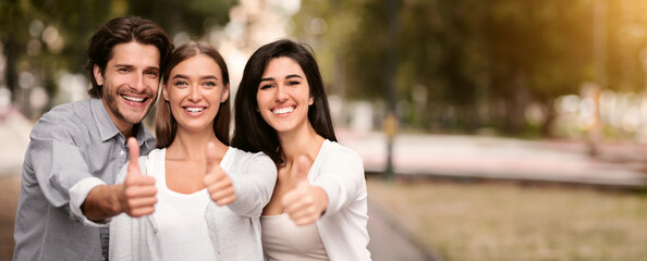 Like. Three Happy Friends Gesturing Thumbs Up Smiling To Camera Standing Outdoor.