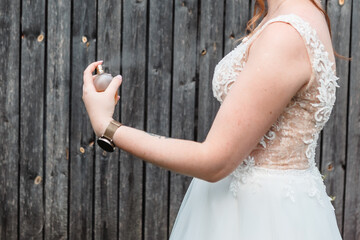 
beautiful slender woman's hand sprays perfume on a white dress, wedding time, white woman