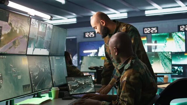 Army colleagues looking at screens in command center housing operational missile defense system designed to intercept ballistic rockets. Experts using tracking gear and radar systems, camera B