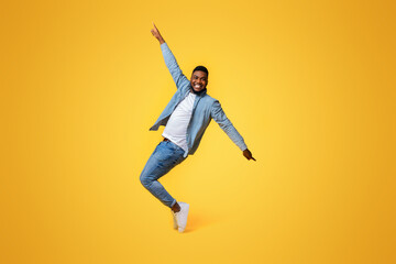 Cheerful Black Standing On Tiptoes, Fooling Over Yellow Background In Studio