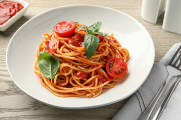 Delicious pasta with tomato sauce and basil served on wooden table, closeup