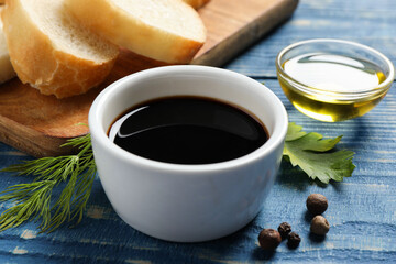 Balsamic vinegar, bread and other products on blue wooden table, closeup