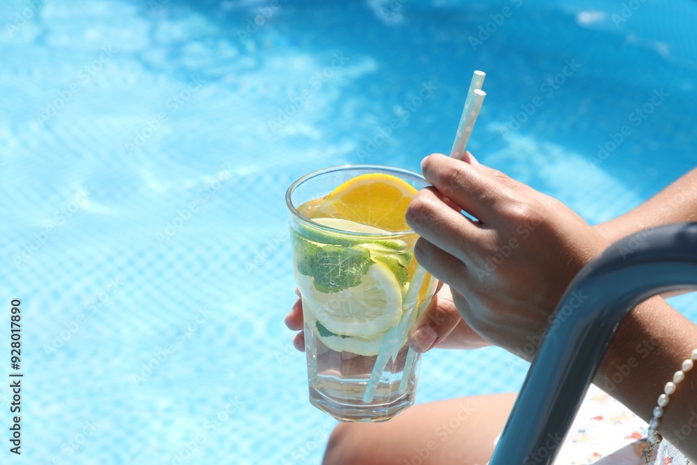 Wall mural woman holding tasty cocktail in glass near swimming pool outdoors, closeup