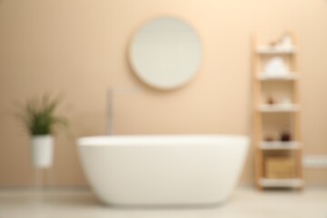Blurred view of bathtub, houseplant, shelving unit and mirror in stylish bathroom