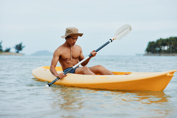 Happy Asian Man Enjoying Kayaking Adventure on Tropical Beach