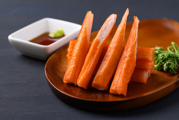 Crab sticks on wooden plate eating with wasabi and sauce