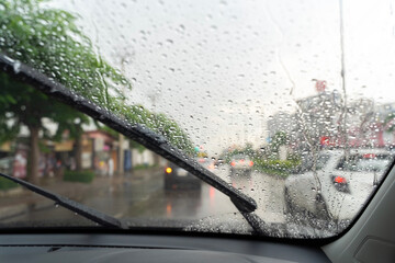 Car windshield with rain drops and frameless wiper blade closeup. © jittawit21