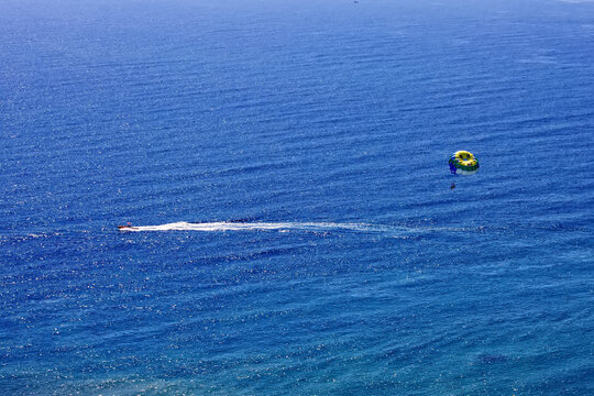 Blue parasail wing pulled by a boat. Sea summer recreation Alicante. white boat mark remains on the blue sea.