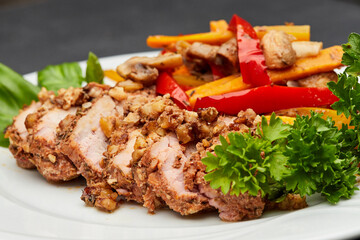 Tender sliced meat with roasted vegetables and fresh herbs on a white plate