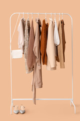 Rack with stylish clothes on beige background