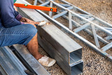 A man is sitting on the ground and working on a metal structure