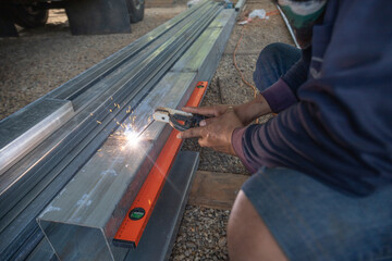 A man is sitting on the ground and working on a metal structure.