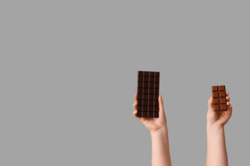 Female hands with different sweet chocolate on grey background