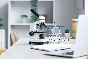 Modern microscope with molecular model on table in teenager's room, closeup