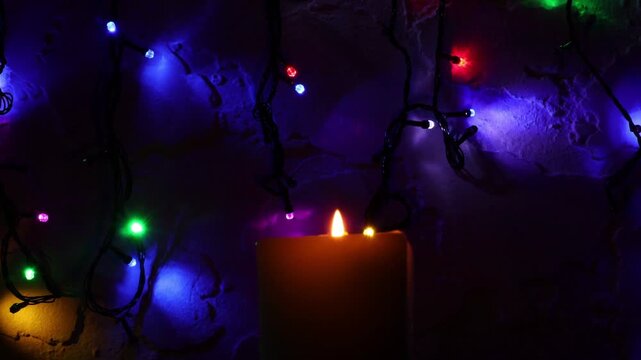Primer plano de una vela blanca con llama rodeada de varias luces con bombillos de varios colores en movimiento en la oscuridad - Powered by Adobe