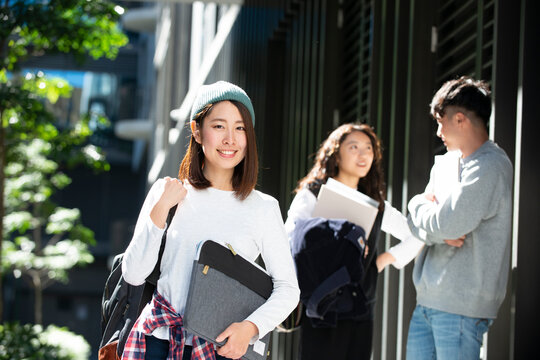 パソコンポーチを抱えて笑っている女子学生