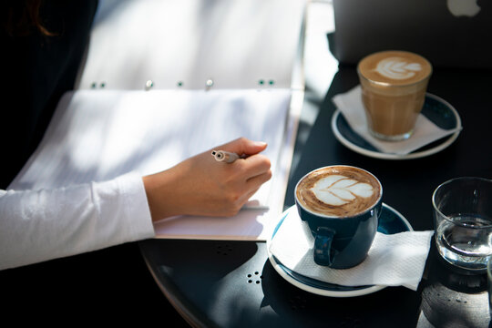 カフェでノートを開いて作業をしている人の手元