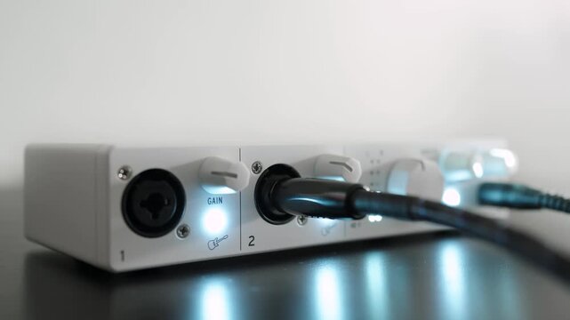 Audio interface on a table. Cables connected and lights flashing