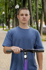 a slender guy on an electric scooter walks along the park, eco-friendly electric transport.