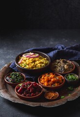 An assortment of vibrant, flavorful vegetarian Pakistani dishes, including biryani rice, served in small wooden bowls on a rustic platter, garnished with fresh herbs and onions