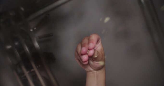 Beautiful slow motion shot of a chef's hand throwing oregano directly into the camera lens focusing from below in a low light restaurant kitchen.