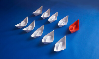 One Single Red Paper Ship Among White Paper Boats On Blue Background. Minimal Individuality, Leadership Or Think Different Idea
