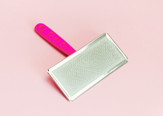 pink animal hair cleaning comb on pink background. Grooming tool for dogs and cats.