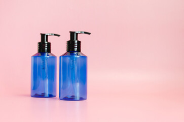 two plastic translucent blue bottles isolated on pink background. template, cosmetic dispenser