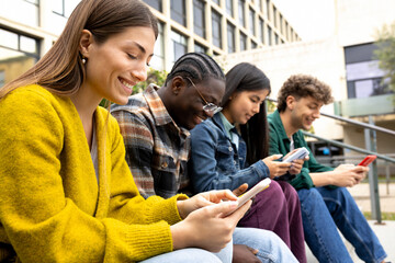 Group of happy multiracial teenage college friend students ignoring each other looking at mobile phone. Smartphone addiction.