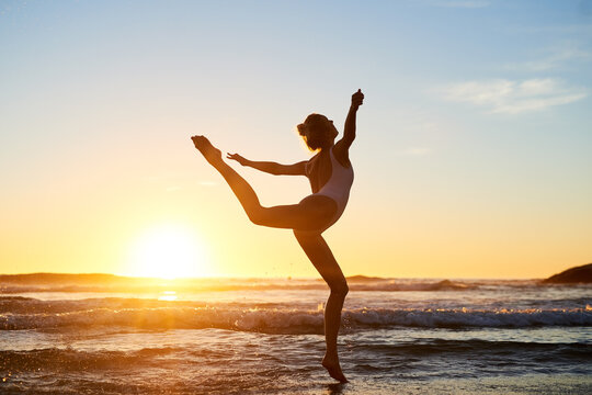 Girl, dancer artist and ocean for ballet at sunset, travel and practice balance movement by waves. Female person, freedom and dancing at dusk for performance, stretching and creative talent at sea